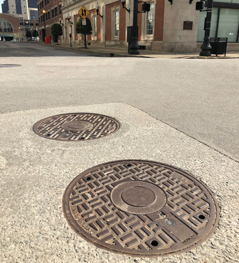 Explosion mitigation manhole covers installed in roadway