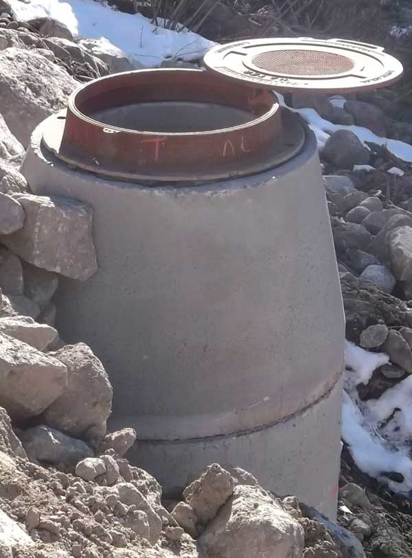 Revolution access assembly installed on a mountainside raised manhole structure